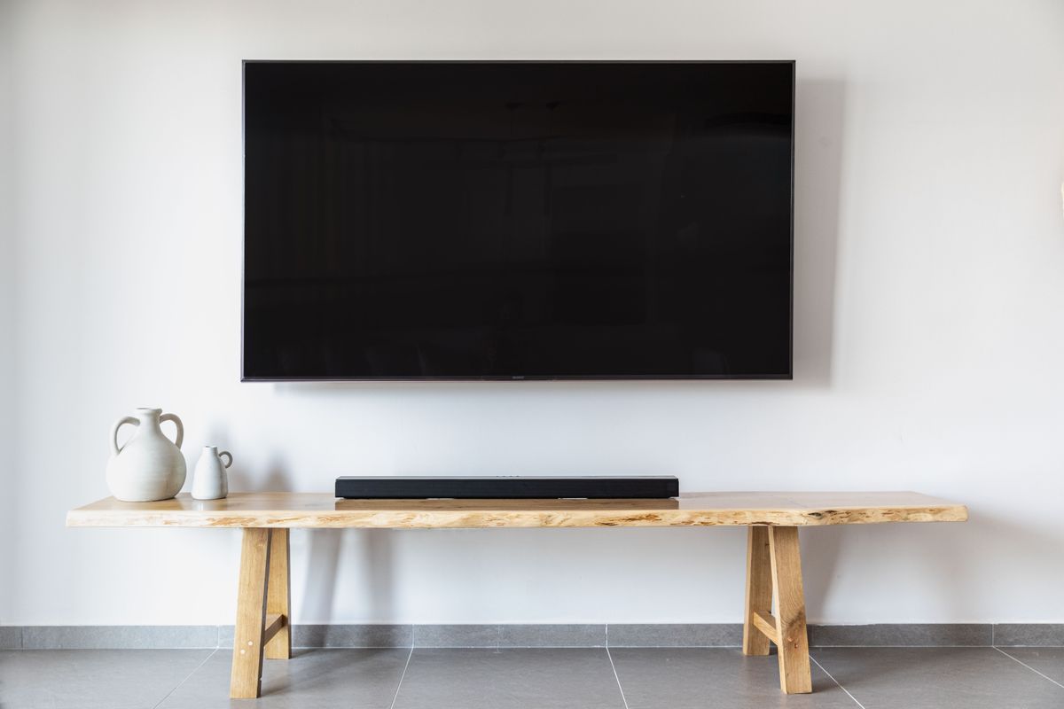 Minimalist living room with a wall-mounted TV above a wooden console, illustrating feng shui TV placement