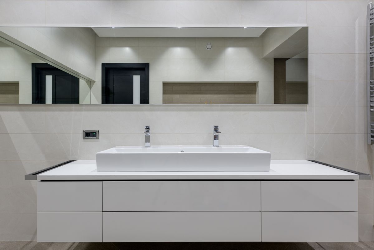 Bright bathroom interior with mirror wall and glass shower partition