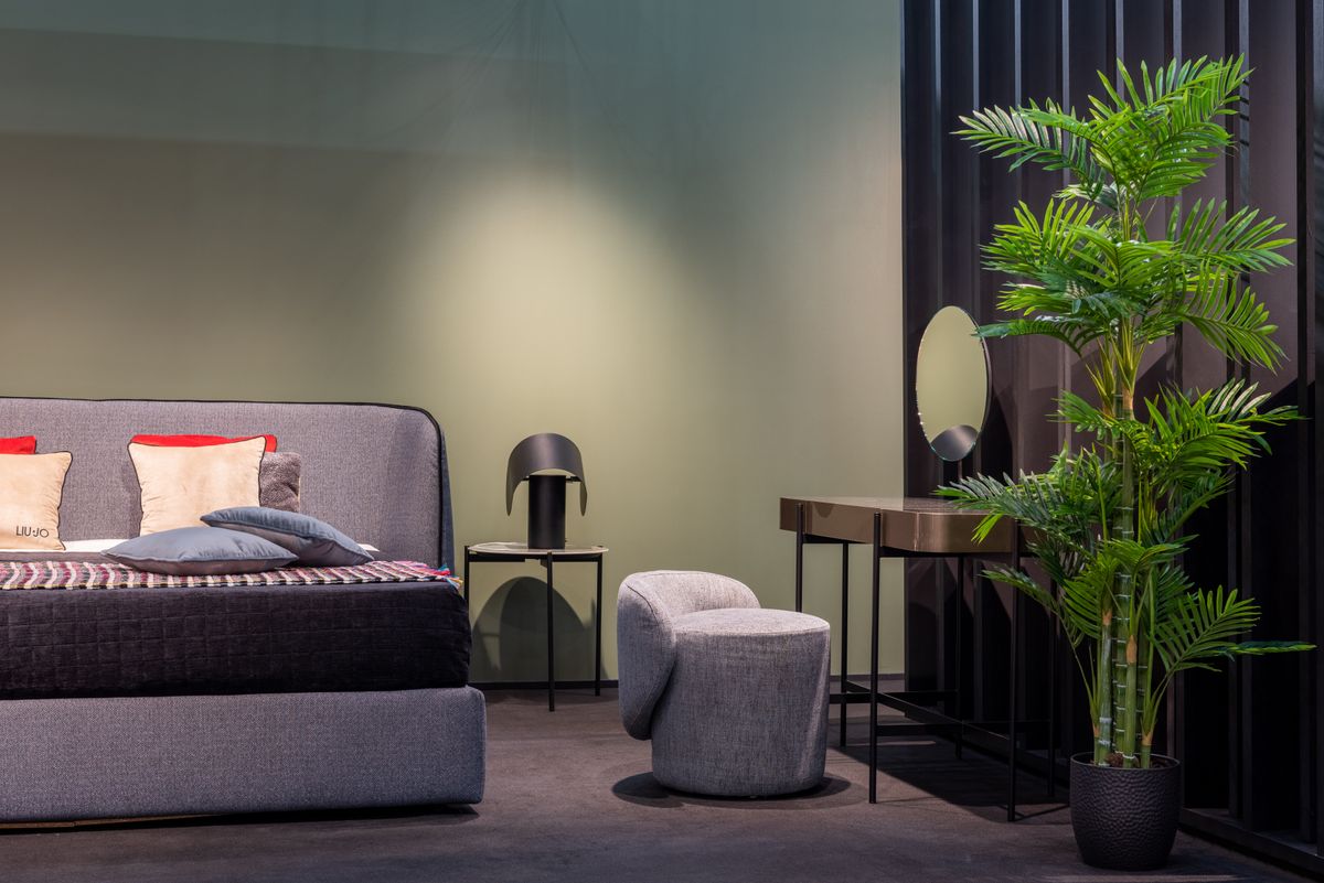 Cozy bedroom with a potted plant beside the bed and a dressing table, illustrating gentle feng shui natural elements