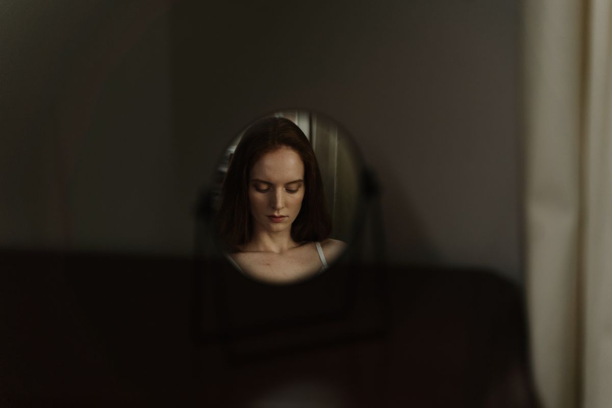 Contemplative round mirror reflection composition for mirror dream symbolism Woman reflected in a round mirror with soft focus creating a contemplative composition about self-perception in dreams