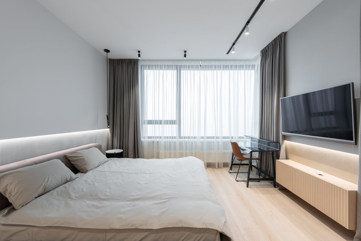 Modern bedroom with a flat-screen TV mounted opposite the bed, illustrating electronics to avoid in feng shui