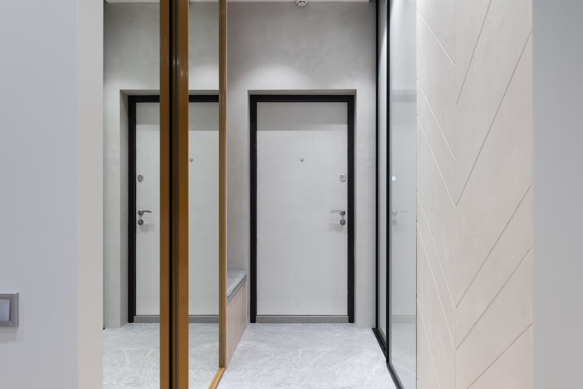 Built-in floor-to-ceiling mirrored wardrobes illustrating a fitted mirror wardrobe design Built-in floor-to-ceiling wardrobes with mirrored panels along a hallway wall as a built-in mirror wardrobe design