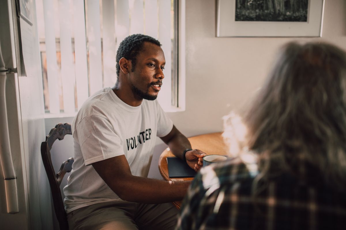 Two people in warm conversation indoors symbolising social self and looking-glass self psychology Two people having a thoughtful conversation in warm lighting illustrating social reflection and Cooley looking-glass self concept