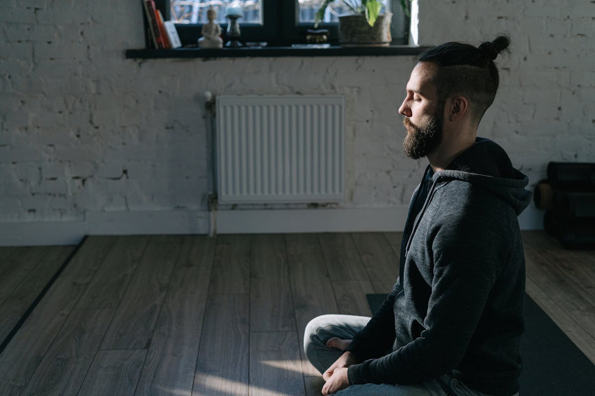 A man in a relaxed meditative posture sitting calmly in a peaceful indoor setting, embodying inner stillness and self-acceptance