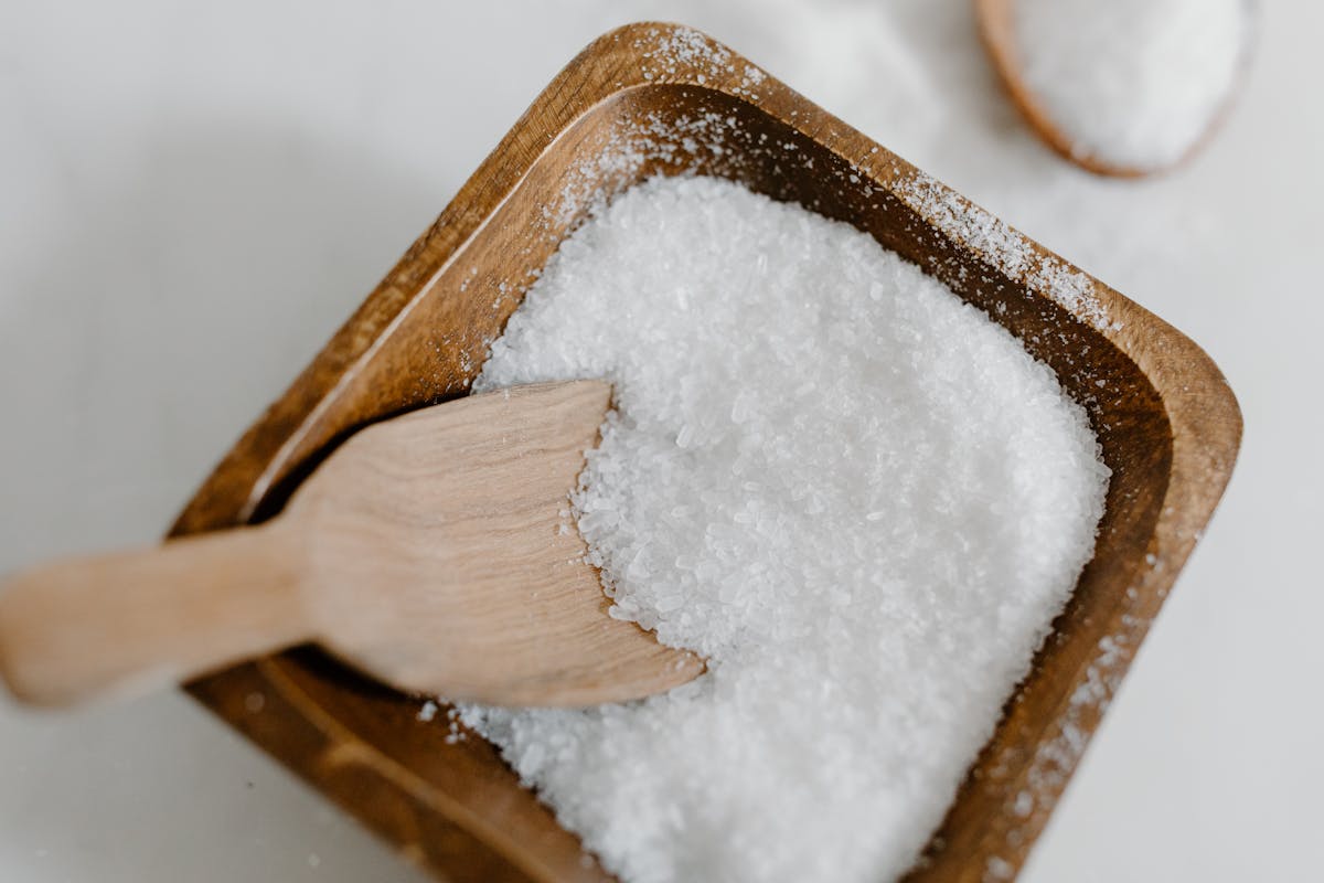Sea salt crystals piled in a wooden bowl beside soft natural kitchen light