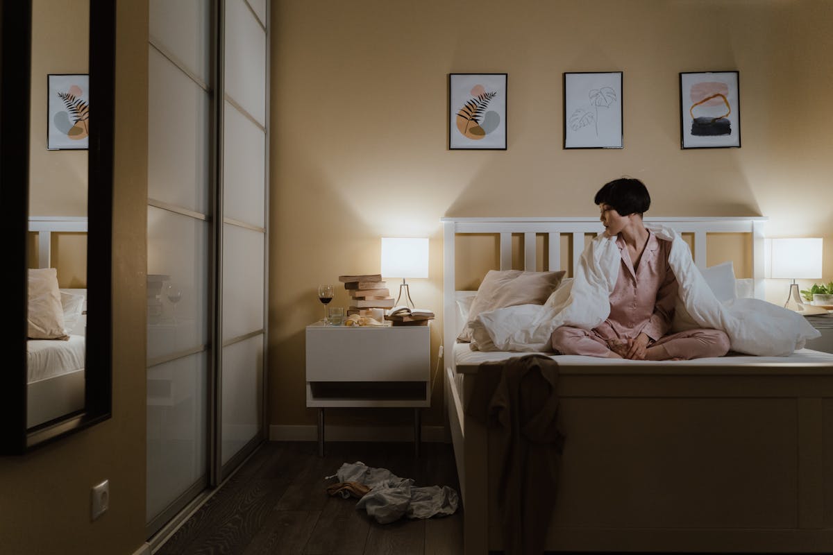 Warmly lit bedroom at night illustrating how a mirror over the bed can affect sleep Woman resting in a warmly lit bedroom at night, relating to whether a mirror facing the bed disrupts sleep