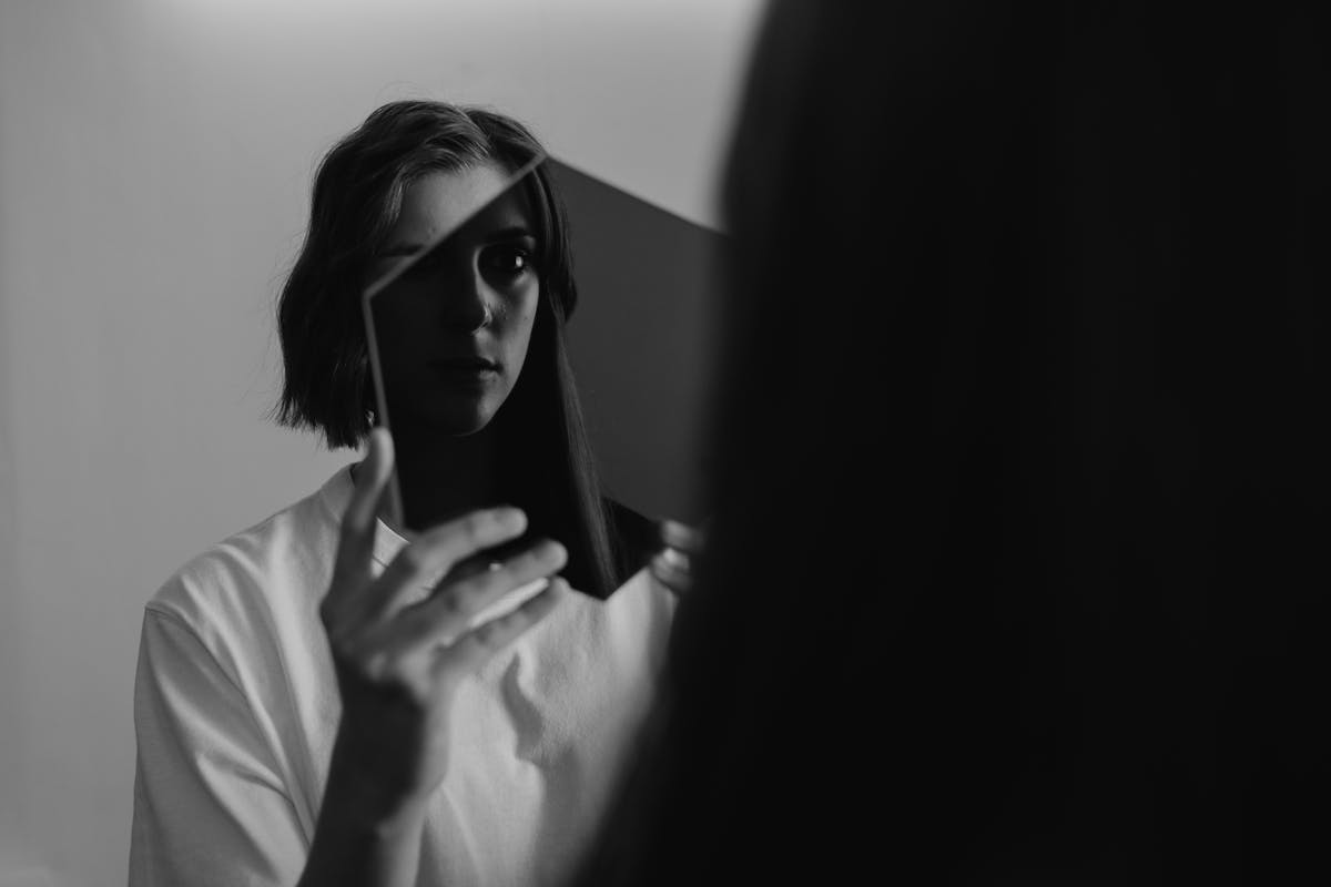 Woman reflecting on herself in mirror in black and white for self-awareness and mirror psychology Monochrome image of a woman reflecting on herself in a mirror evoking self-awareness and mirror psychology
