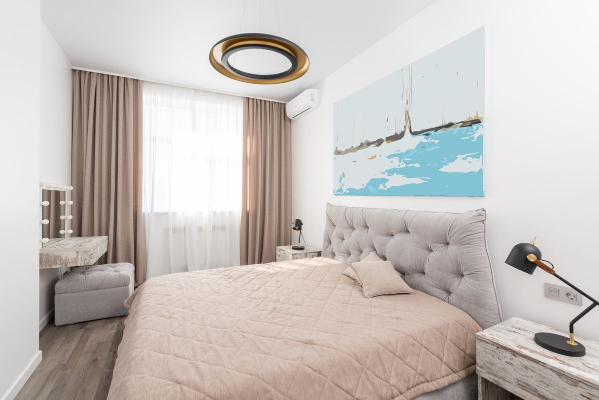 Bedroom with a wall mirror illustrating how a mirror opens up a small bedroom Modern bedroom with a mirror, bed and bedside lamps, illustrating using a mirror as bedroom wall decor