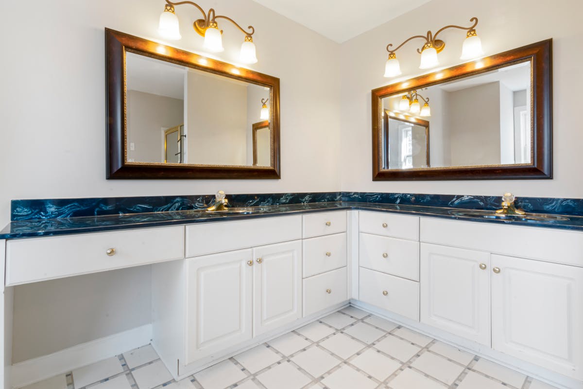 Bathroom vanity with mirrors illustrating how high to hang a vanity mirror Spacious bathroom with dual mirrors and elegant lighting, illustrating vanity mirror placement height