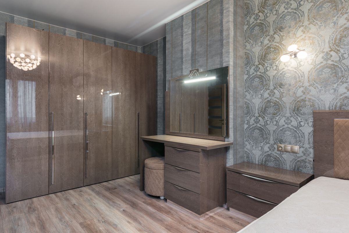 Chest of drawers with an attached mirror showing a matched dresser and mirror set Glossy chest of drawers with an attached mirror in a bedroom as a dresser-and-mirror set