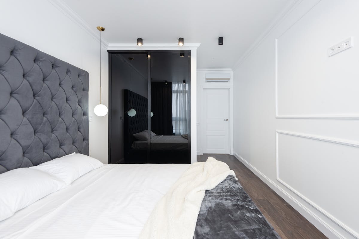 Simple uncluttered bedroom illustrating feng shui bedroom mistakes to avoid Clean contemporary bedroom with a grey headboard and uncluttered white walls, illustrating what to avoid in feng shui
