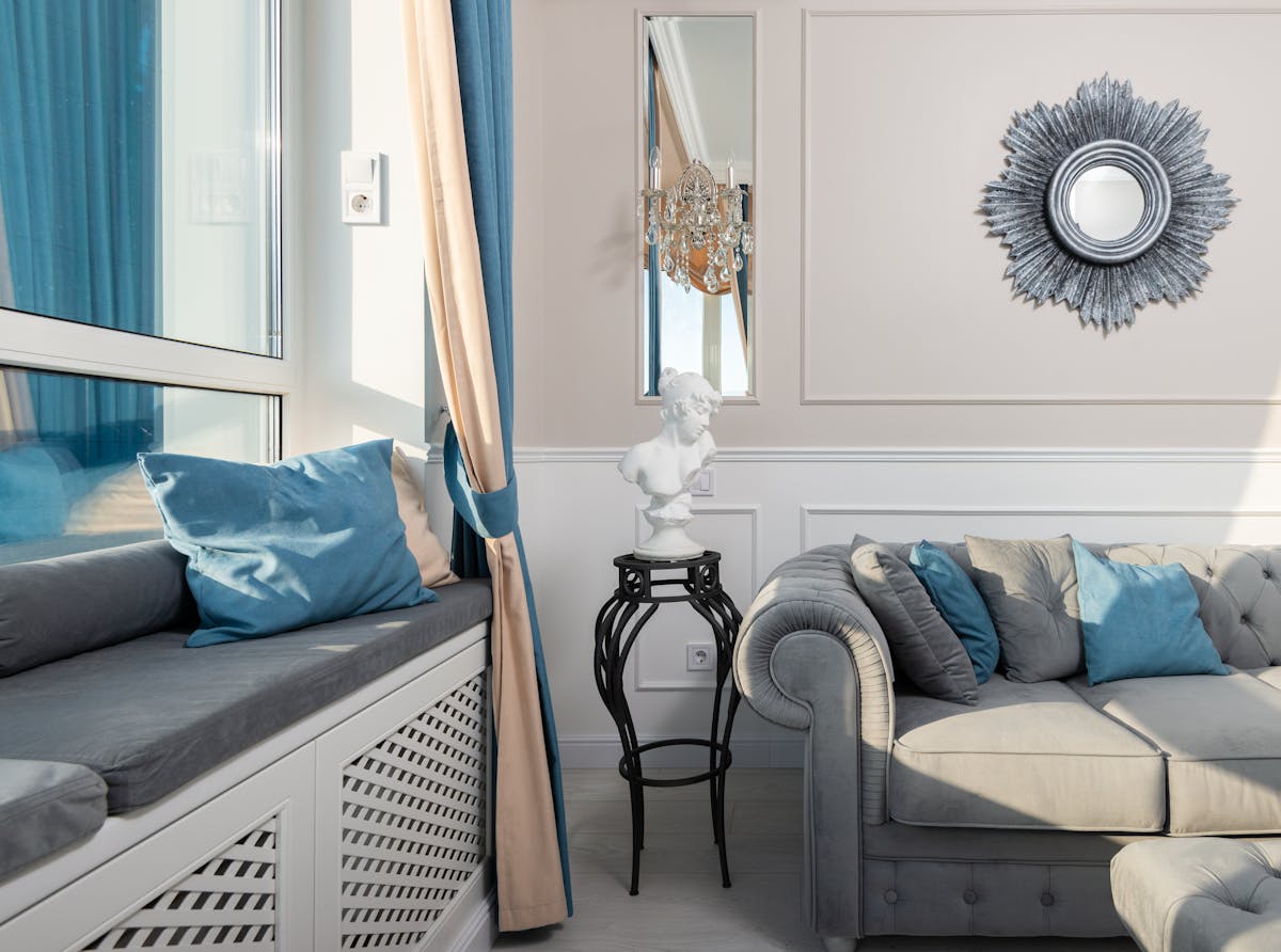 Mirror hung above a sofa illustrating the correct height and spacing over a couch Sofa with cushions beneath a wall mirror on a sunny day, illustrating mirror over sofa height and placement
