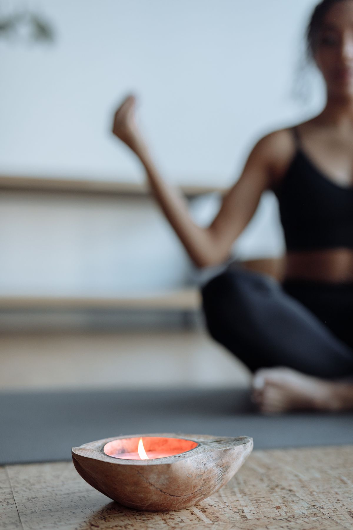 Woman meditating by candlelight evoking Trataka gazing practice and sustained inward attention A woman meditates on a yoga mat with a lit candle in focus creating a calming atmosphere suggesting the Trataka practice of sustained focused gazing