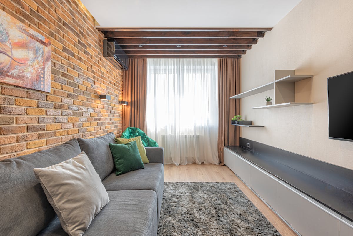 Living room with a rustic exposed brick wall and a gray sofa, illustrating a brick accent wall