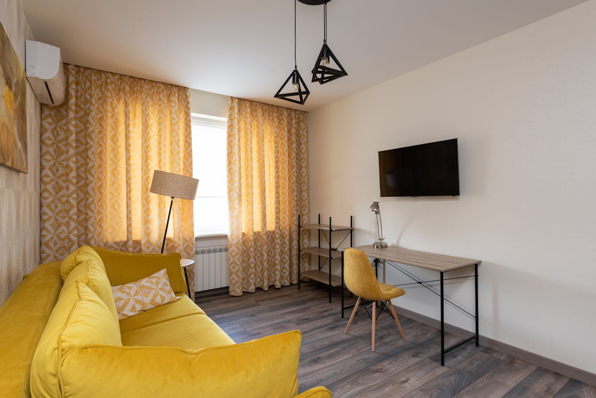 Modern living room in warm yellow tones with sofa and cushions, illustrating warm feng shui social colors