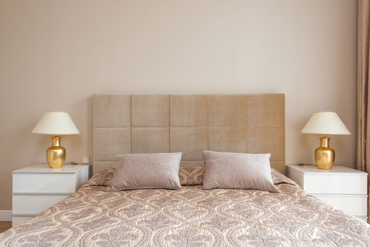 Symmetrical bedroom with paired nightstands and lamps illustrating feng shui balance Bedroom with a soft headboard and a matching lamp and nightstand on each side, illustrating feng shui symmetry