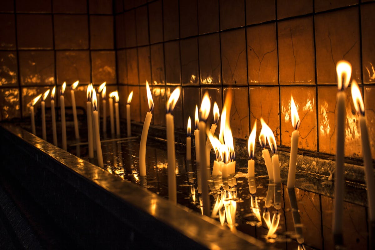 Lit candles reflecting softly on a dark polished surface evoking the conditions of a black mirror scrying session