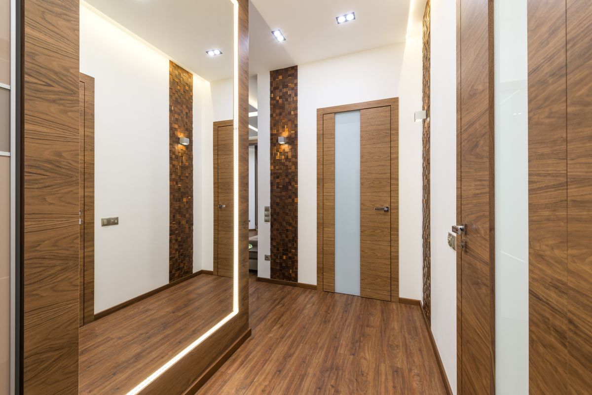 Sleek contemporary hallway with wooden elements and warm light, showing mirror shapes for a narrow hallway