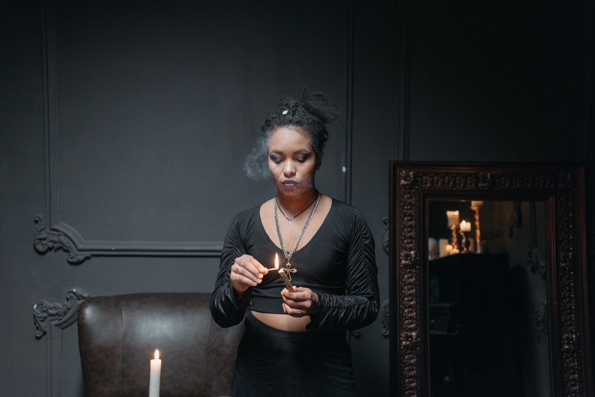 Person lighting a match in a dim ritual setting representing the deliberate preparation and safety required for black mirror scrying