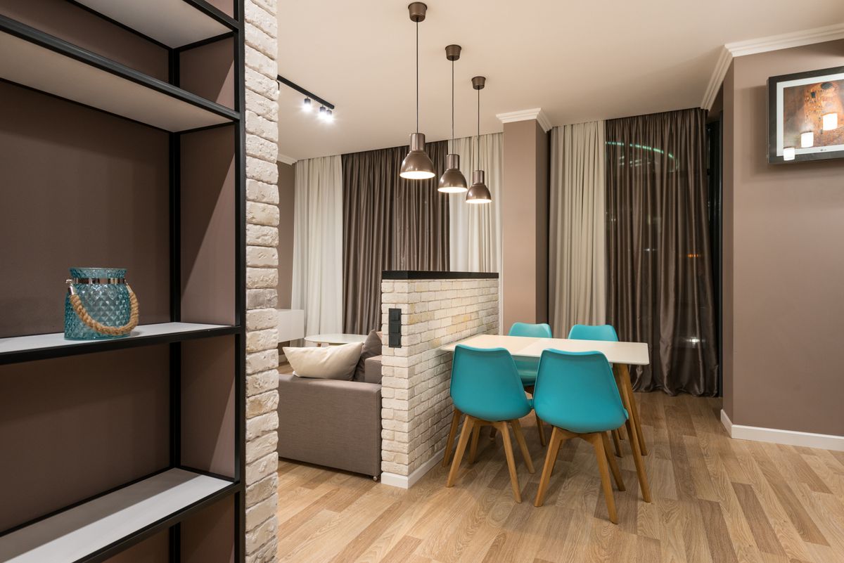 Studio work area divided by a partition illustrating feng shui separation of work and rest Small apartment with a table and chairs near a brick partition, illustrating separating a work zone in feng shui