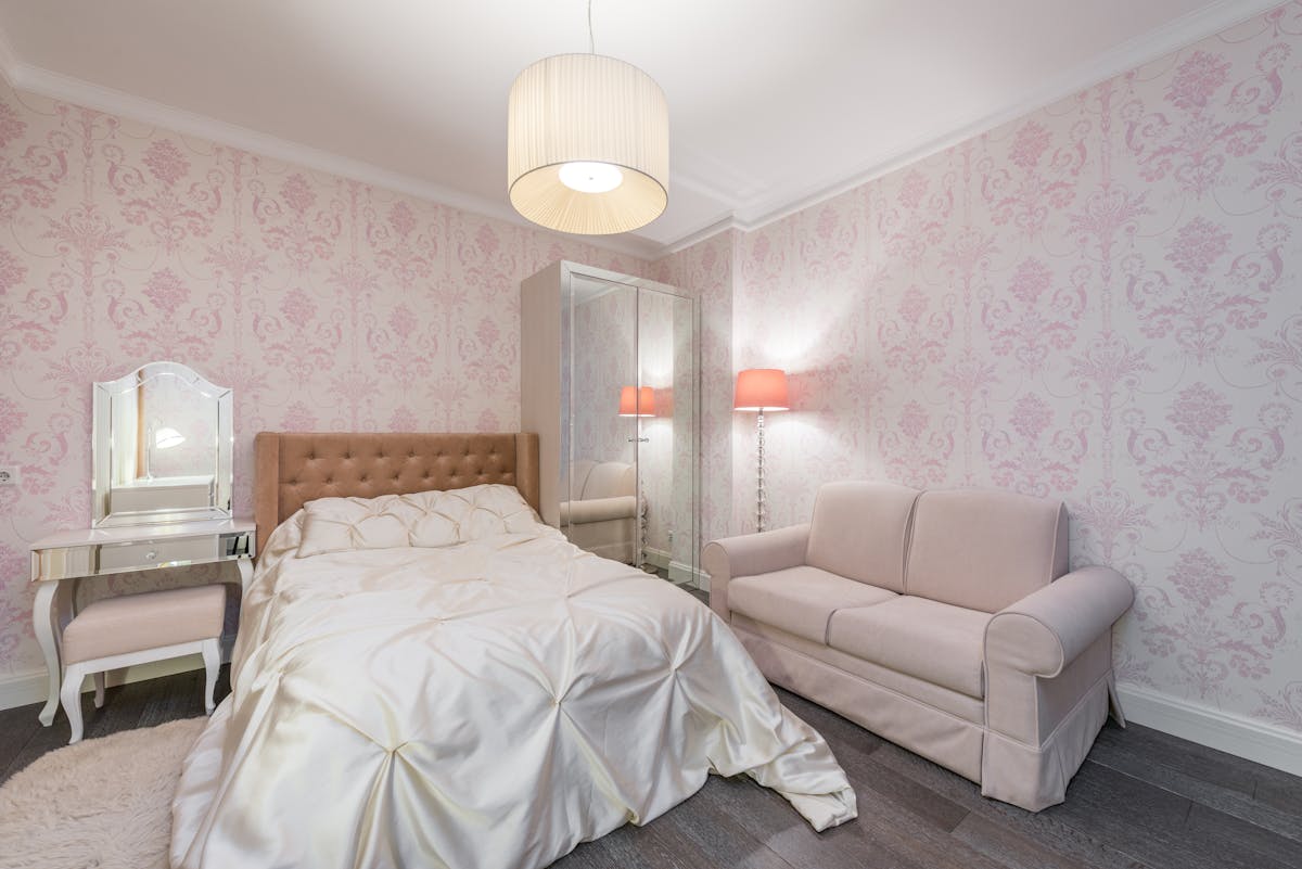 Spacious contemporary bedroom with soft pink walls and white linen, illustrating feng shui colors for romance