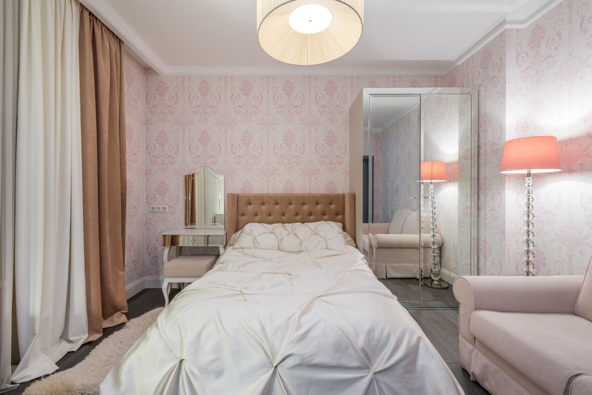 Bedroom with glowing bedside lamps positioned next to a wall mirror showing how mirrors over nightstands reflect light