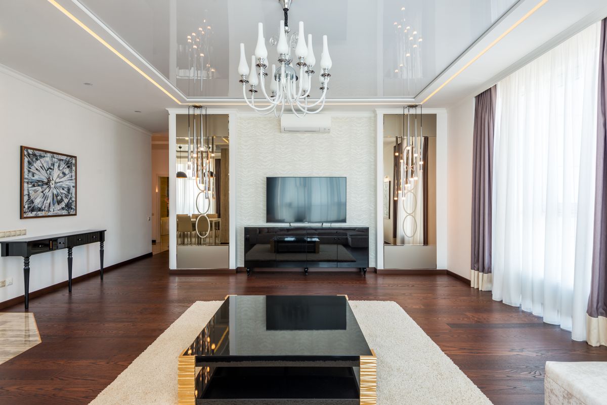 Stylish living room illustrating why a mirrored accent wall adds light and space Stylish living room with a chandelier and modern decor, illustrating why a mirrored accent wall works