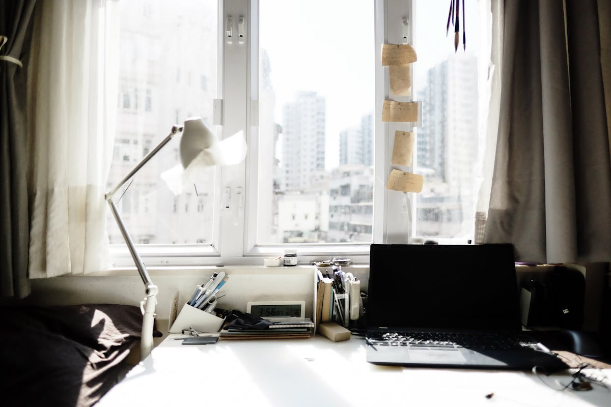 Desk beside a window illustrating window placement in a feng shui office layout Bright home workspace with a laptop and lamp beside a large window, illustrating feng shui desk placement near a window