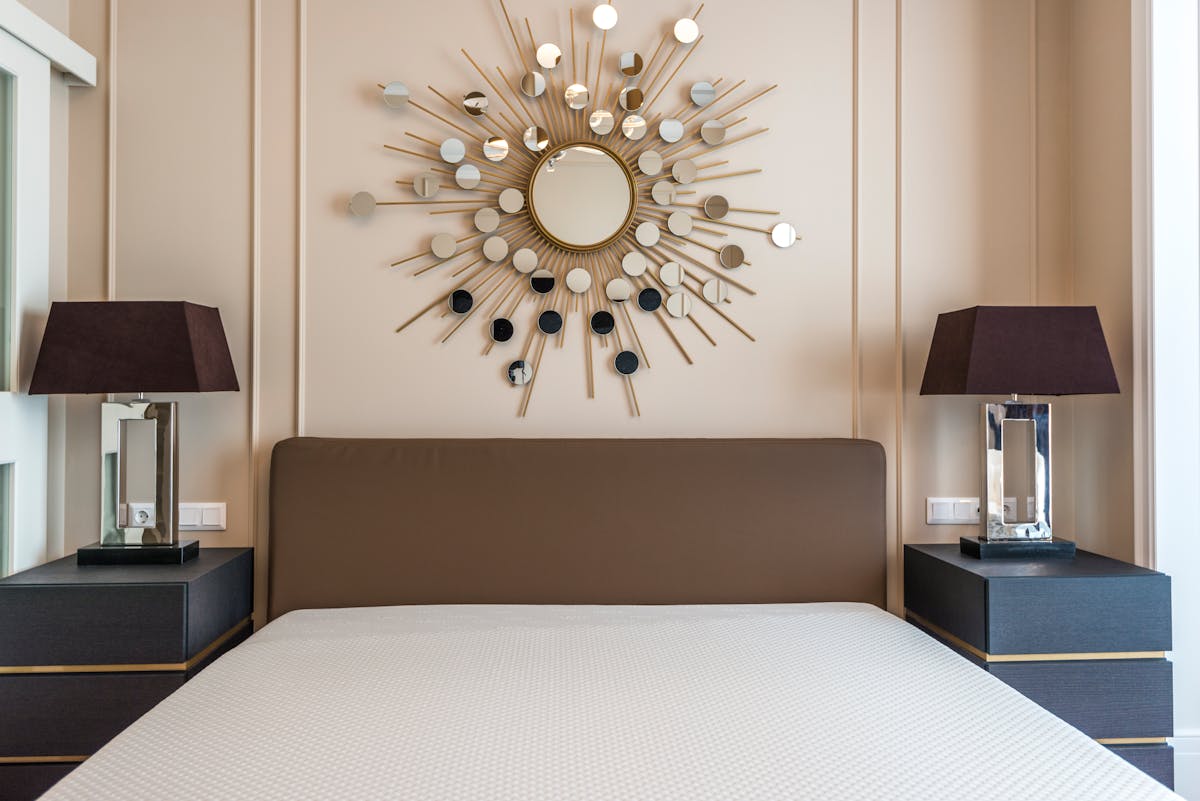 Stylish bedroom with matching lamps on symmetrical bedside tables, illustrating the feng shui rule of pairs
