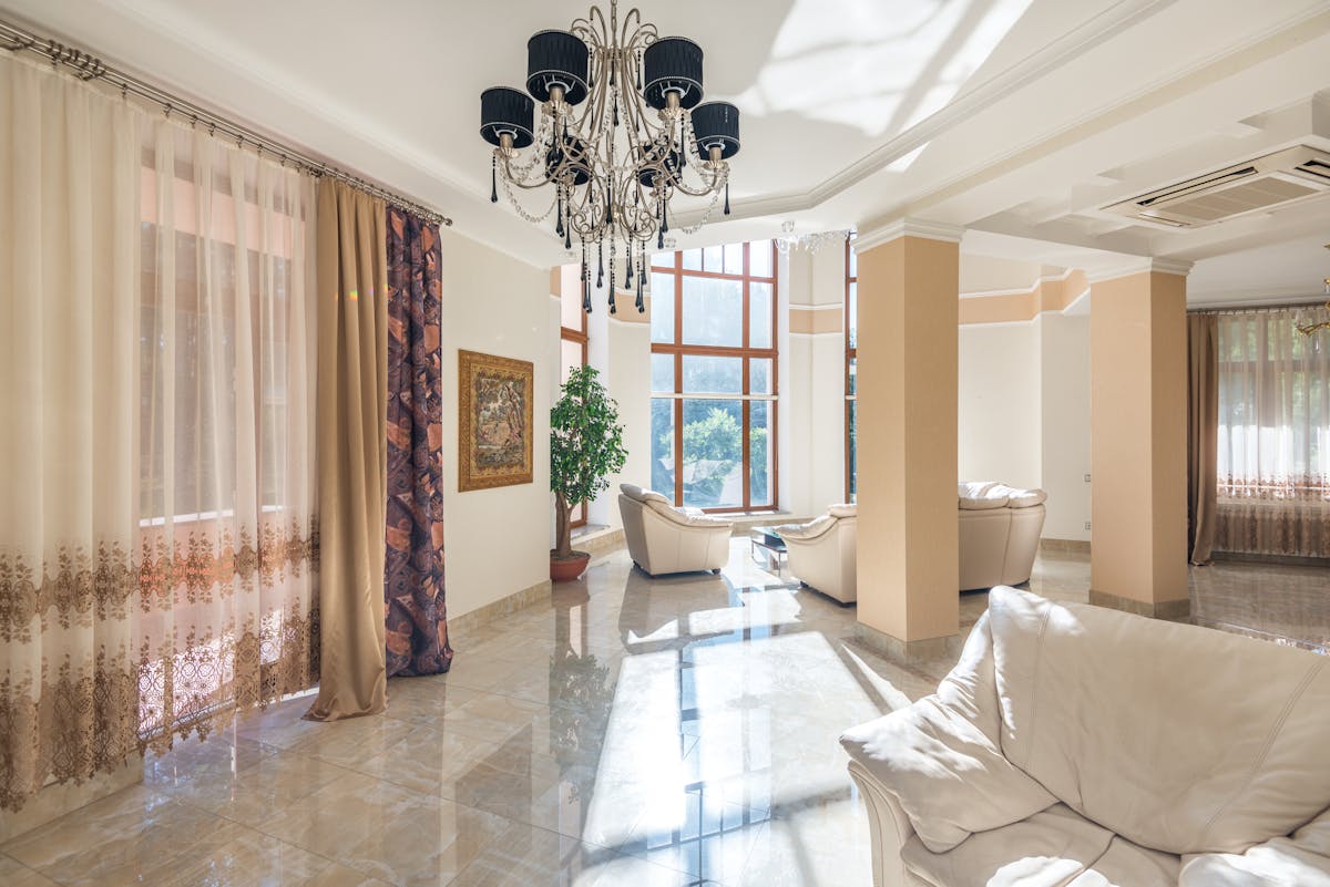 Bright spacious living room with chandelier large windows and soft seating Mediterranean elegance