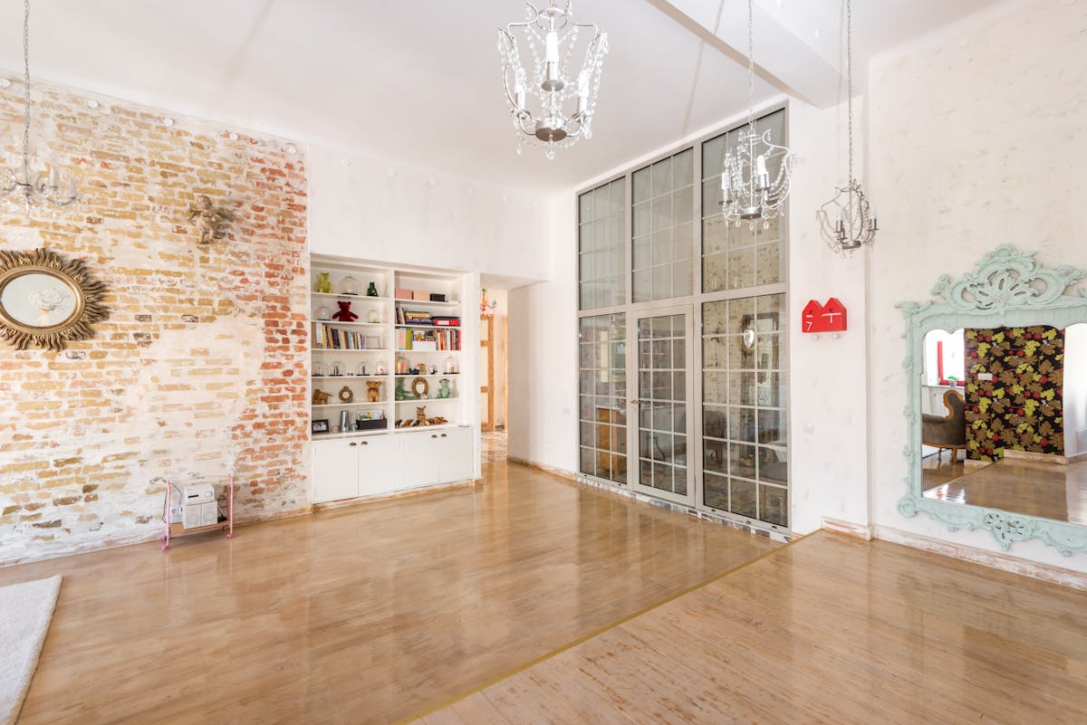 Cluster of mirrored frames illustrating a living room mirror gallery wall idea Bright room with multiple mirrored frames on a brick wall, illustrating a mirror gallery cluster