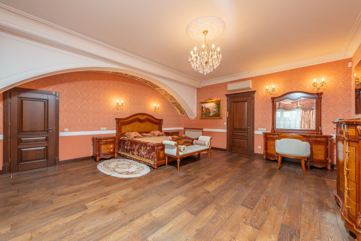 Classic bedroom with elegant furniture illustrating how to style an arched mirror in a bedroom Luxurious classic bedroom with vintage wooden furniture and chandelier lighting, illustrating arched mirror bedroom ideas