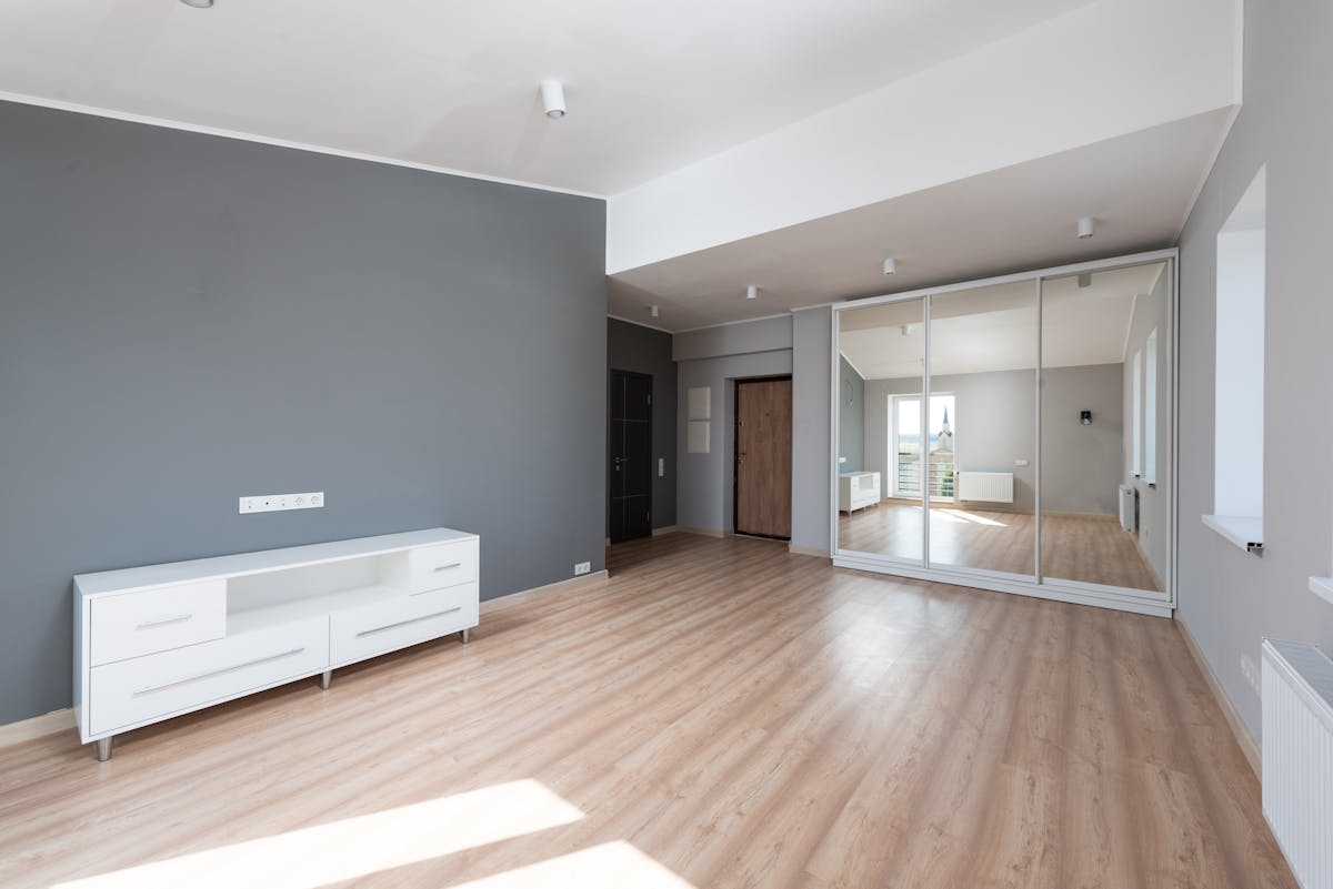 Minimalist room with a tall full length mirror illustrating how to size a full length mirror Spacious minimalist room with wooden flooring and a tall full length mirror, illustrating full length mirror sizing