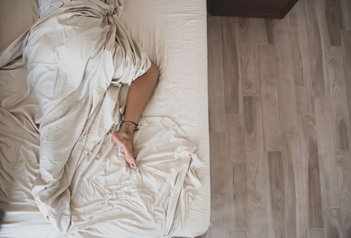 Person sleeping peacefully under white sheets seen from above, illustrating the feng shui sleeping direction question