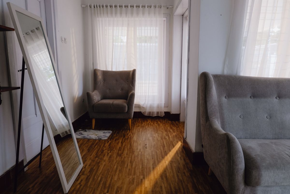 Light-filled living room illustrating positioning a mirror over a sofa to reflect light Bright living room with grey sofas and natural light, illustrating what a mirror over a sofa should reflect