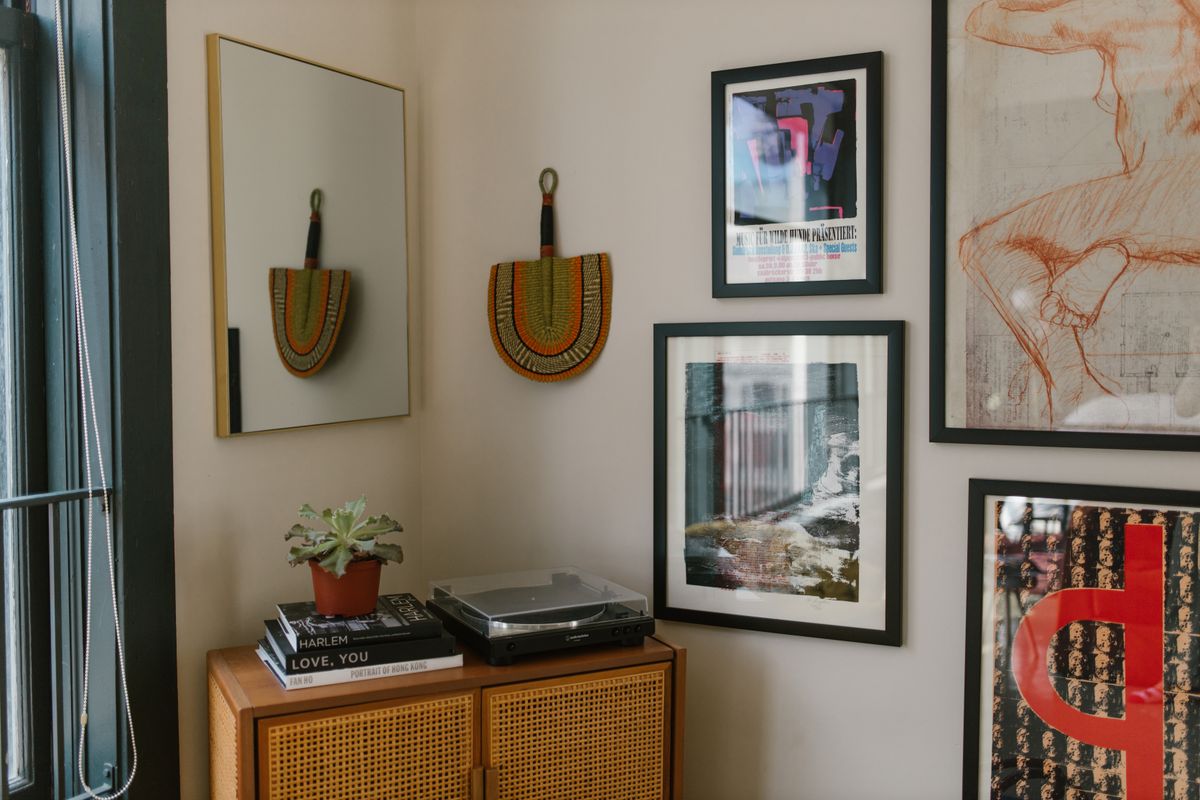 Wood-framed mirror styled on a wooden cabinet illustrating why a wood mirror frame adds warmth Cozy interior with framed art, a wood-framed mirror, and a small plant on a wooden cabinet, illustrating why wood mirror frames work