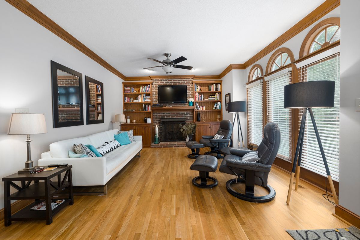 Bright living room illustrating how to size an arched mirror for a wall Elegant living room with a couch, armchair, and fireplace in a bright space, illustrating arched mirror sizing
