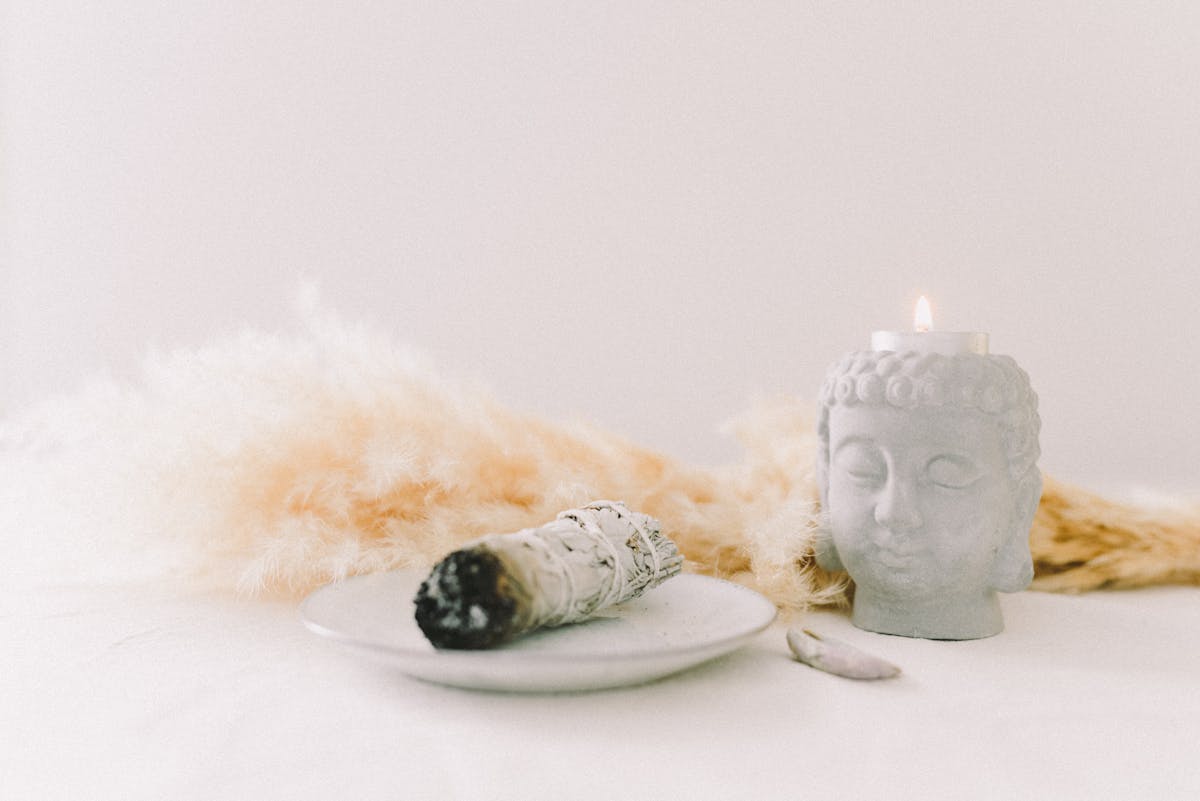 Sage bundle and Buddha candle holder with pampas grass in a serene arrangement representing the ritual atmosphere of mirror scrying practice