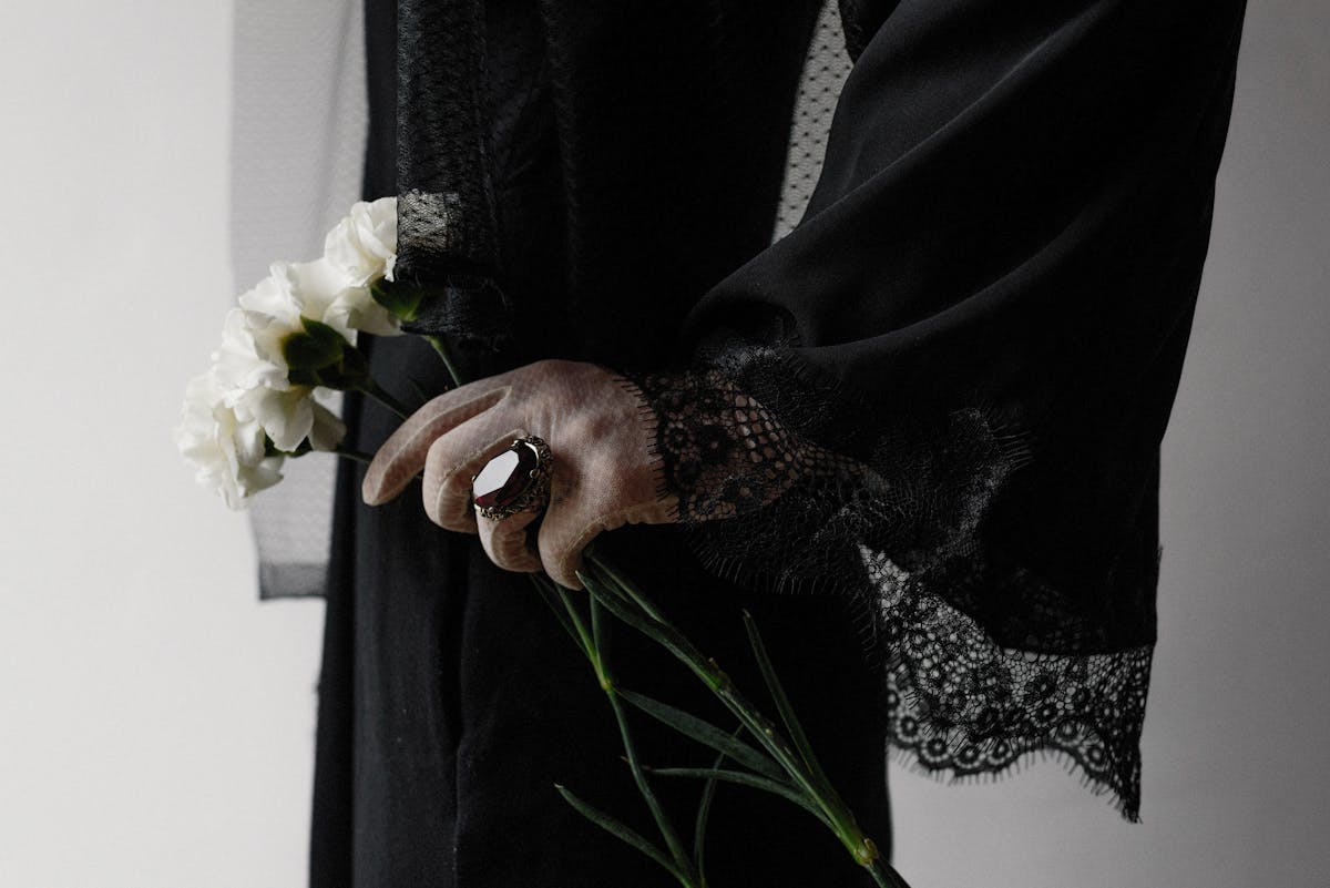 A woman in a black mourning dress holding flowers, symbolizing funeral traditions and grief
