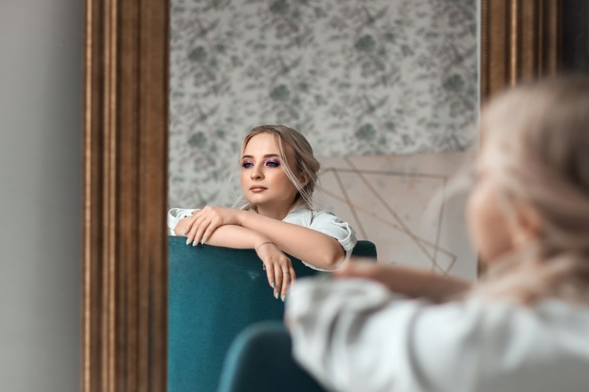 Elegant woman before decorative mirror emphasizing depth cues and diminishing repeated reflections discussed in optics